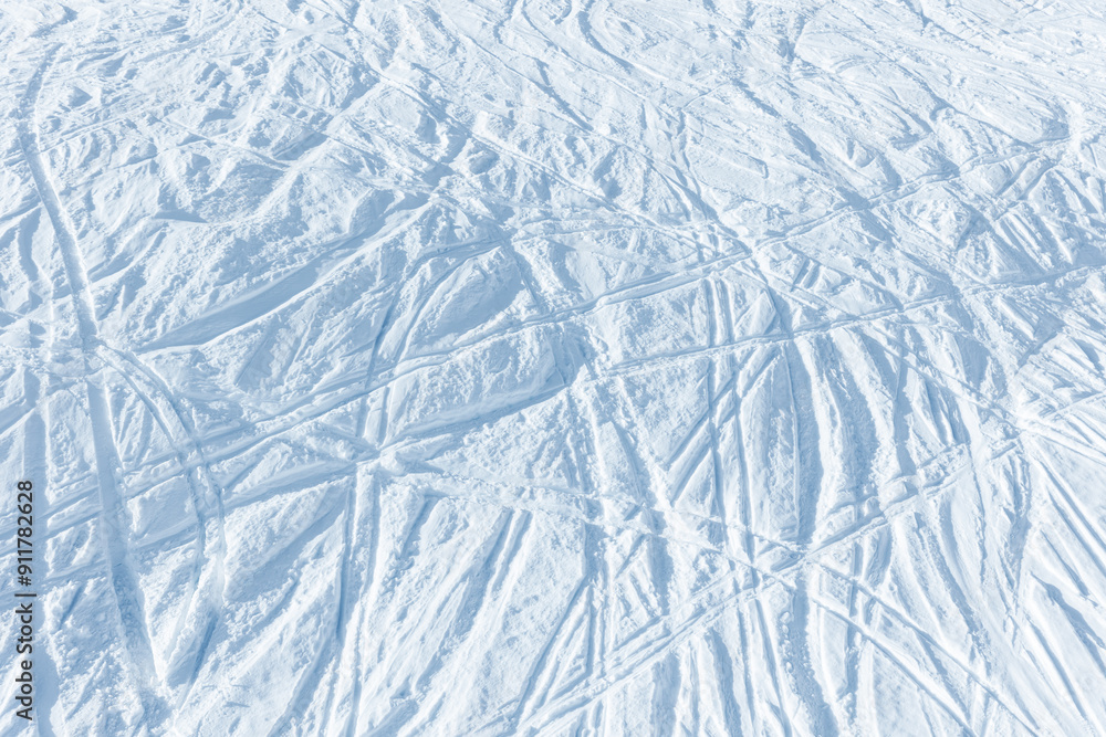 Snowy abstract off-piste skiing background with ski and snowboard trails and tracks on new virgin powder snow. morning sunrise or evening sunset time at alpine mountain resort Snowy abstract off-piste skiing background with ski and snowboard trails and tracks on new virgin powder snow. morning sunrise or evening sunset time at alpine mountain resort
