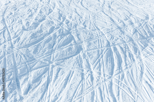 Snowy abstract off-piste skiing background with ski and snowboard trails and tracks on new virgin powder snow. morning sunrise or evening sunset time at alpine mountain resort