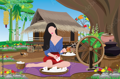 A young country girl is spinning cotton under a big tree in front of her hut.