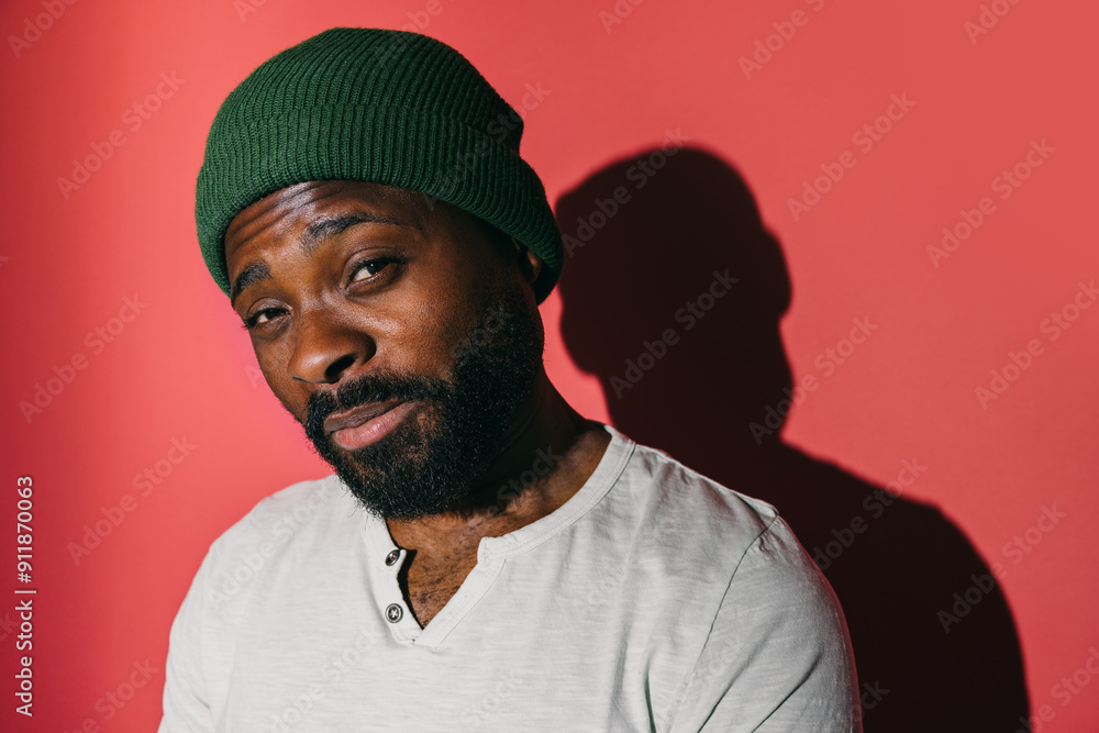 Man wearing a green beanie posing against a red background Man wearing a green beanie posing against a red background
