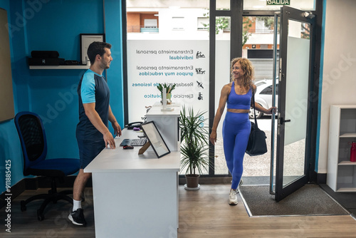 woman entering at a gym where her personal trainer receives her