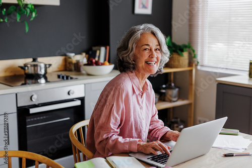 Happy woman working remotely from home using laptop photo