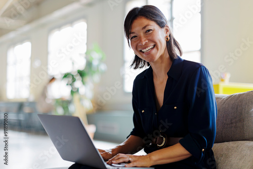 Smiling corporate businesswoman working on laptop in modern office