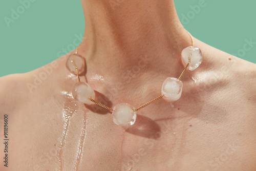 Ice balls pierced with gold chain melting under influence of skin