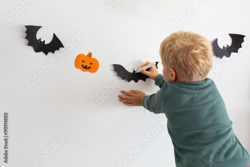 boy decorates the wall before halloween holidays photo