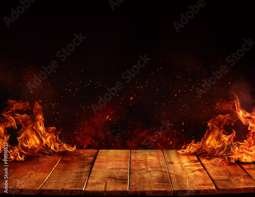 wooden table with Fire burning at the edge of the table, fire particles, sparks, and smoke in the air, with fire flames on a dark background to display products	and spicy foods