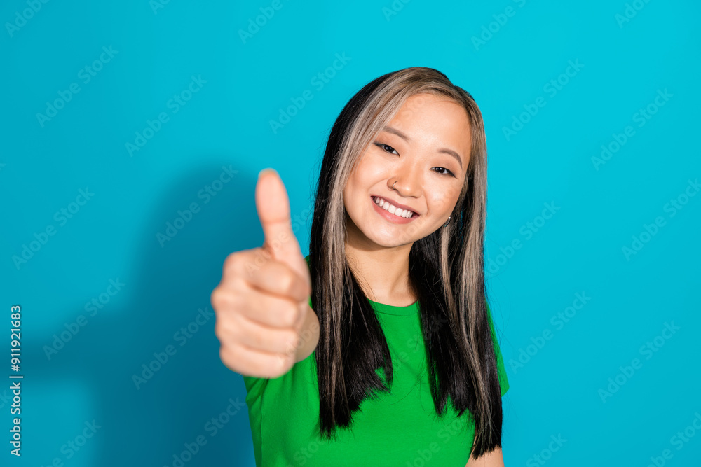 Photo of lovely young girl demonstrate thumb up wear t-shirt isolated on teal color background Photo of lovely young girl demonstrate thumb up wear t-shirt isolated on teal color background