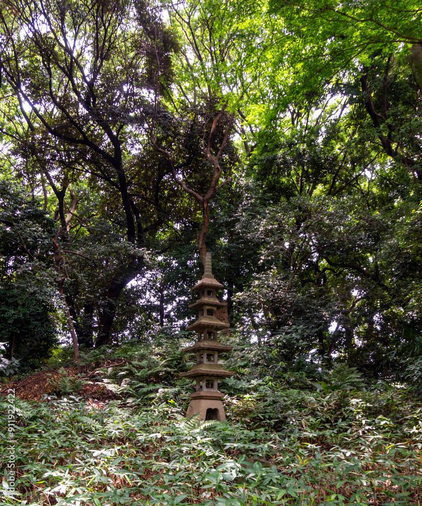 Fototapeta premium Stone Japanese pogoda lantern surrounded by lush greenery and forest in a Japanese garden