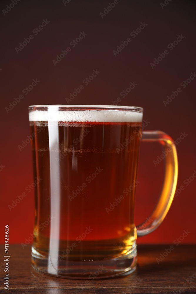Mug with fresh beer on wooden table against color background, closeup Mug with fresh beer on wooden table against color background, closeup
