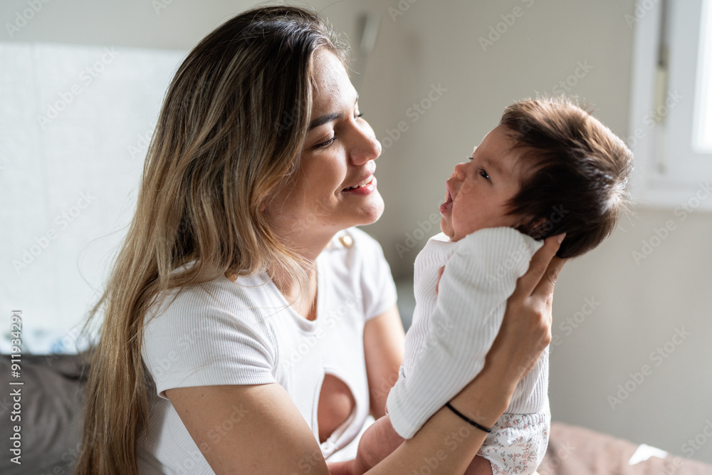 Young mother holding her newborn baby and smiling at home Young mother holding her newborn baby and smiling at home