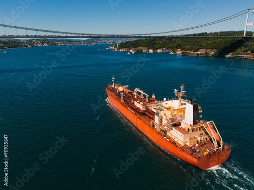 Cargo ship on Bosphorus with suspension bridge photo