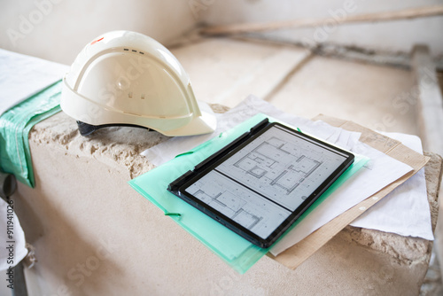 Blueprints On Tablet And Safety Helmet At Construction Site photo