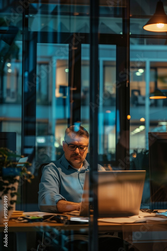 a businessman working alone at night in his office due to work deadlines, stress, overwork in a modern job