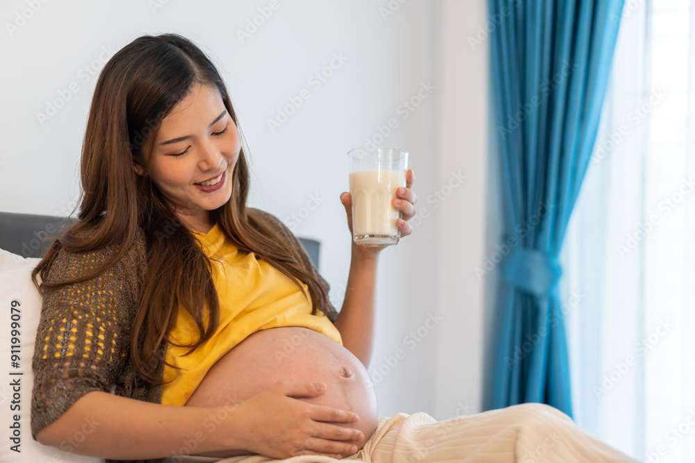 Happy smiling asian mother woman drinking fresh milk hugging with pregnancy baby in belly, woman pregnant, birth, preparation, maternity, protein, nutrition,calcium and vitamin.healthy concept Happy smiling asian mother woman drinking fresh milk hugging with pregnancy baby in belly, woman pregnant, birth, preparation, maternity, protein, nutrition,calcium and vitamin.healthy concept