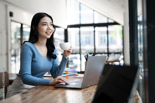 Woman working on laptop online, checking emails and planning on the internet while sitting in an office alone at work.