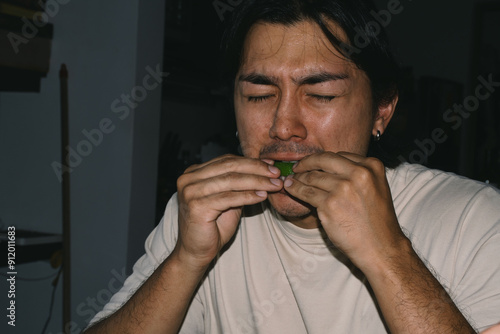 Person eating lemon with sour face 