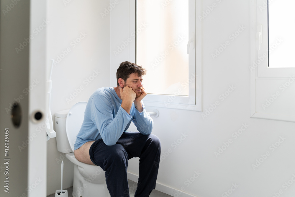 Man sitting on toilet in bathroom Man sitting on toilet in bathroom