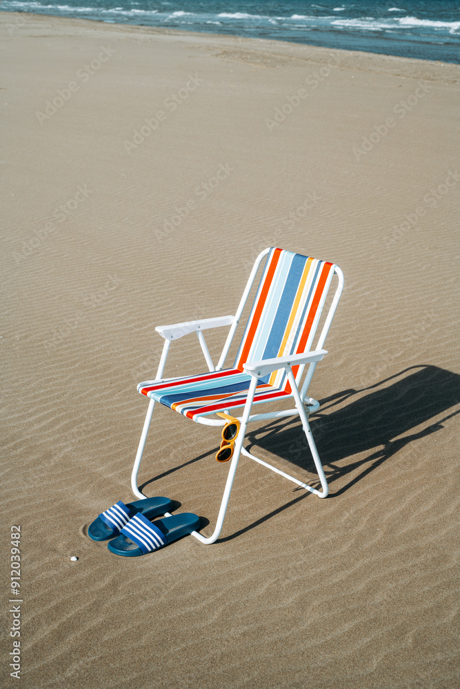 shades, folding chair and sandals on the beach