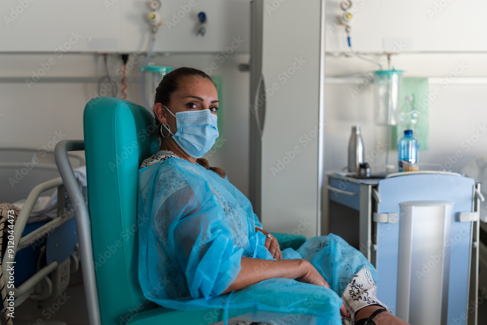 Patient wearing protective gown and mask recovering in hospital room Patient wearing protective gown and mask recovering in hospital room
