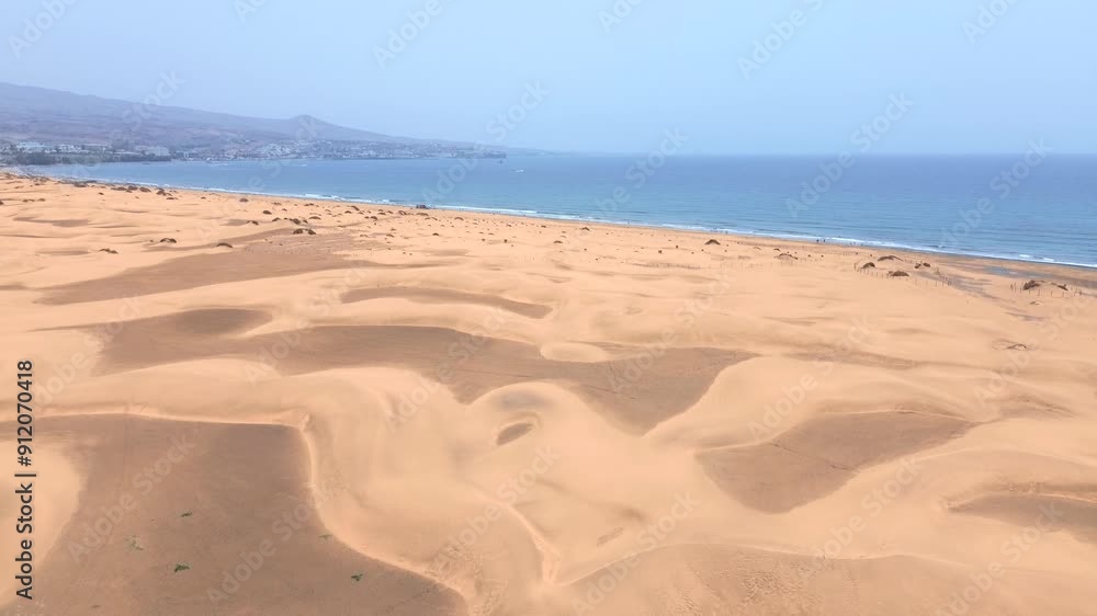 Sand dunes desert against seascape in Maspalomas Gran Canaria deserts near seashore. Aerial drone view of tourists walking thorugh the dunes of Maspalomas in Gran Canaria during a windy day. Sand dunes desert against seascape in Maspalomas Gran Canaria deserts near seashore. Aerial drone view of tourists walking thorugh the dunes of Maspalomas in Gran Canaria during a windy day.