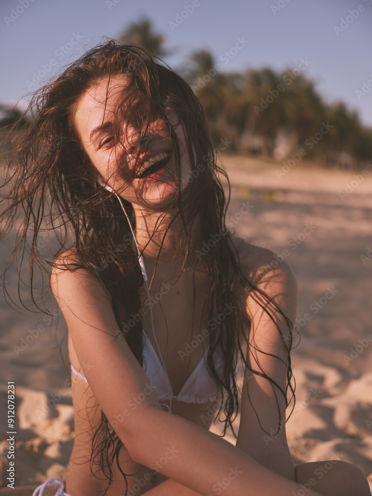 Attractive woman enjoying a relaxing day at the beach, with hair blowing in the wind, wearing a bikini Attractive woman enjoying a relaxing day at the beach, with hair blowing in the wind, wearing a bikini