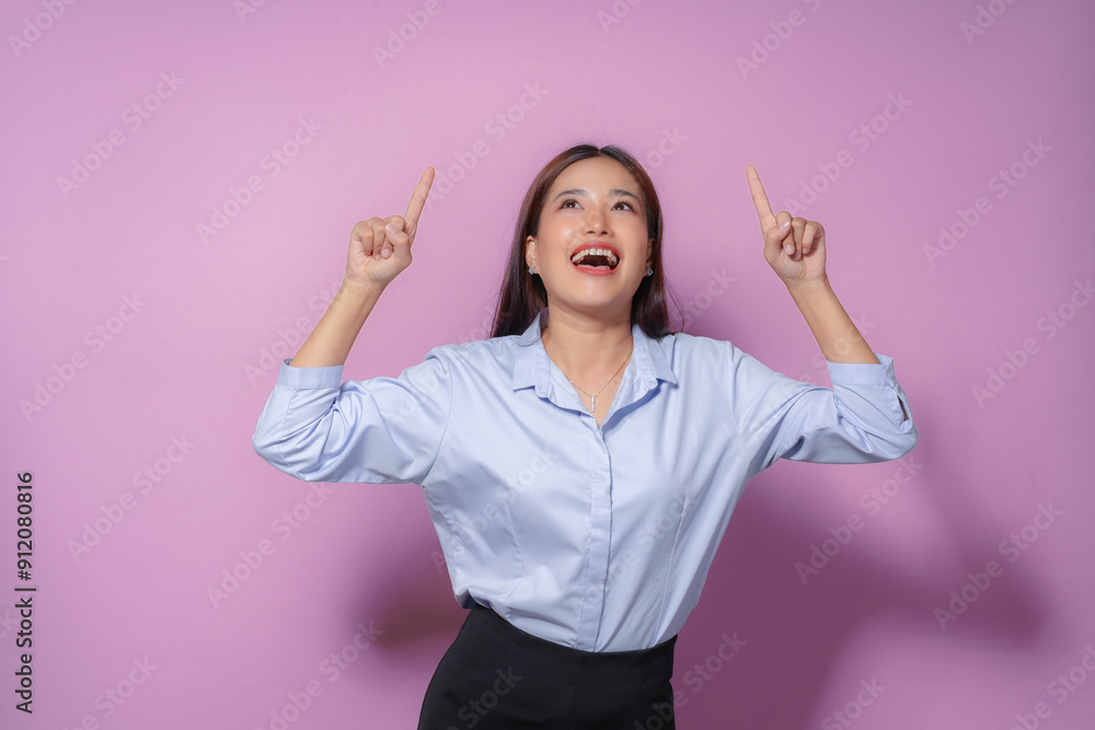 Excited businesswoman is pointing up with both index fingers and smiling, suggesting place for advertisement Excited businesswoman is pointing up with both index fingers and smiling, suggesting place for advertisement
