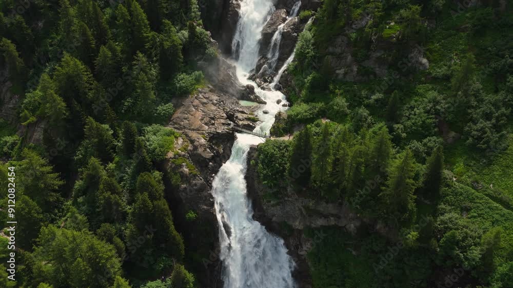 A stunning waterfall cascades through the lush Italian Alps forest, aerial view A stunning waterfall cascades through the lush Italian Alps forest, aerial view