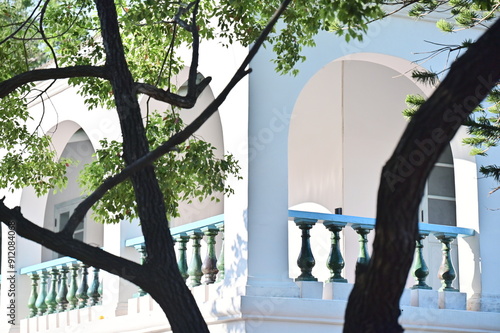 park countryA sunlit outdoor balcony on the second floor of a historic Tainan building, featuring green glazed railing and overlooking a large tree under the clear sky. photo