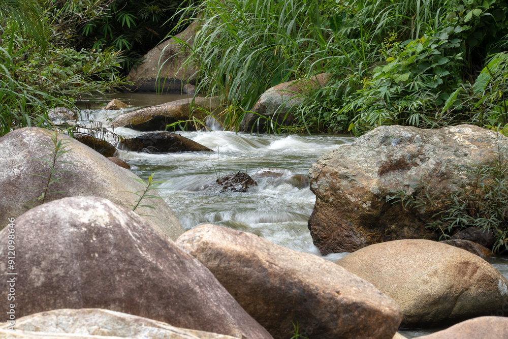 Crystal-clear waterfall dances over smooth stones, weaving a vibrant tapestry through lush green nature Crystal-clear waterfall dances over smooth stones, weaving a vibrant tapestry through lush green nature