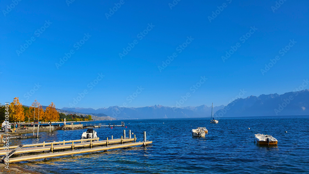 Fototapeta premium Boats on Lake Geneva, Lausanne, Switzerland in autumn, with deep blue water and sky.