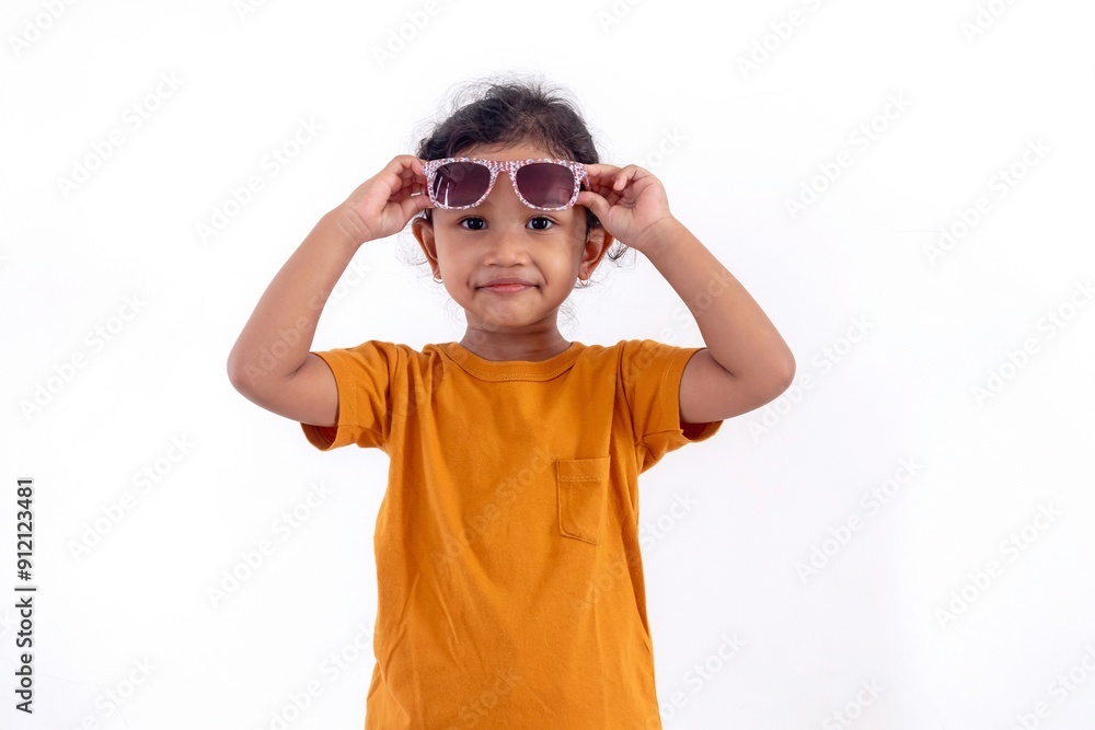 A smiling little Asian girl poses while taking off her glasses A smiling little Asian girl poses while taking off her glasses