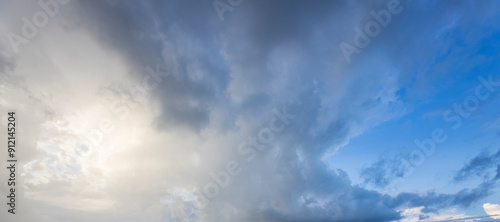 Clouds shift dramatically from dark gray to bright blue, revealing sunlight over a tranquil expanse, showcasing nature's beauty in transition.