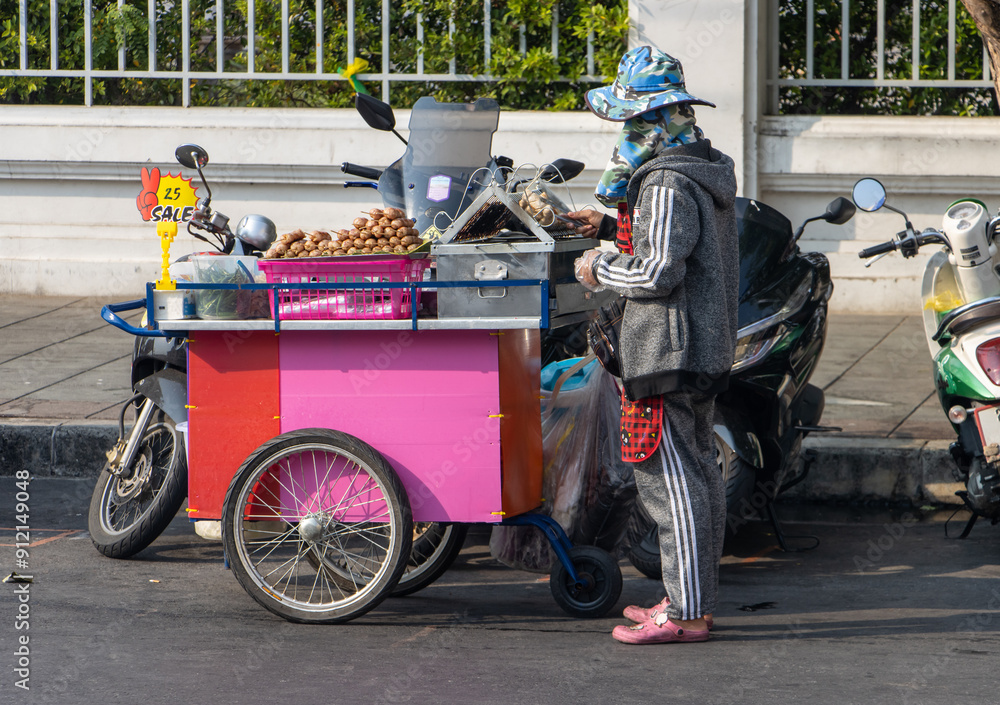 Obraz premium A woman sells grilled meat at a mobile stall on a street in the city center