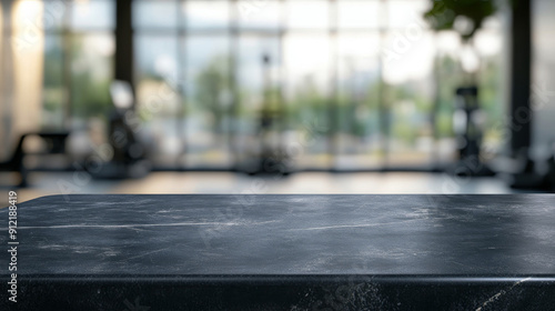 "Empty black marble stone table top set against a blurred background with bokeh effects of an exercise room, fitness center, or gym interior. Ideal for showcasing or presenting your products."