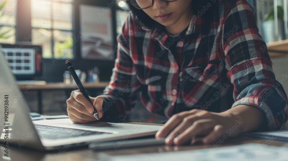 Woman in a modern workspace, deeply engrossed in her work on a laptop and notebook. Woman in a modern workspace, deeply engrossed in her work on a laptop and notebook.