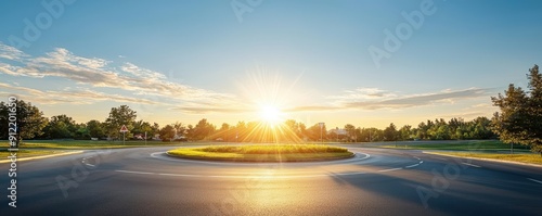 Empty road with a roundabout, surrounded by trees and a vibrant sunset sky. photo