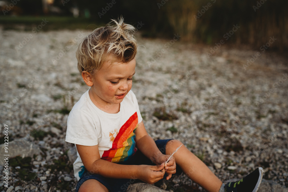 Young child playing outdoors with bird feather full of dirt and mud Young child playing outdoors with bird feather full of dirt and mud