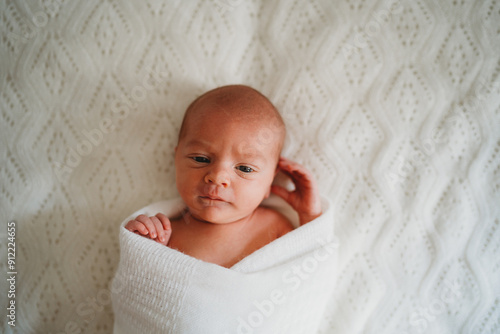 Portrait of calm newborn baby boy wrapped in white photo