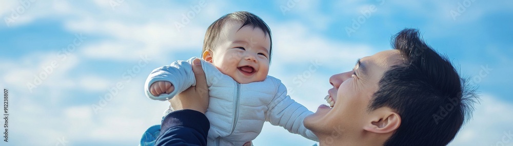 Heartwarming Moment: Dad Lifts Smiling Baby Against a Vibrant Sky Backdrop Heartwarming Moment: Dad Lifts Smiling Baby Against a Vibrant Sky Backdrop