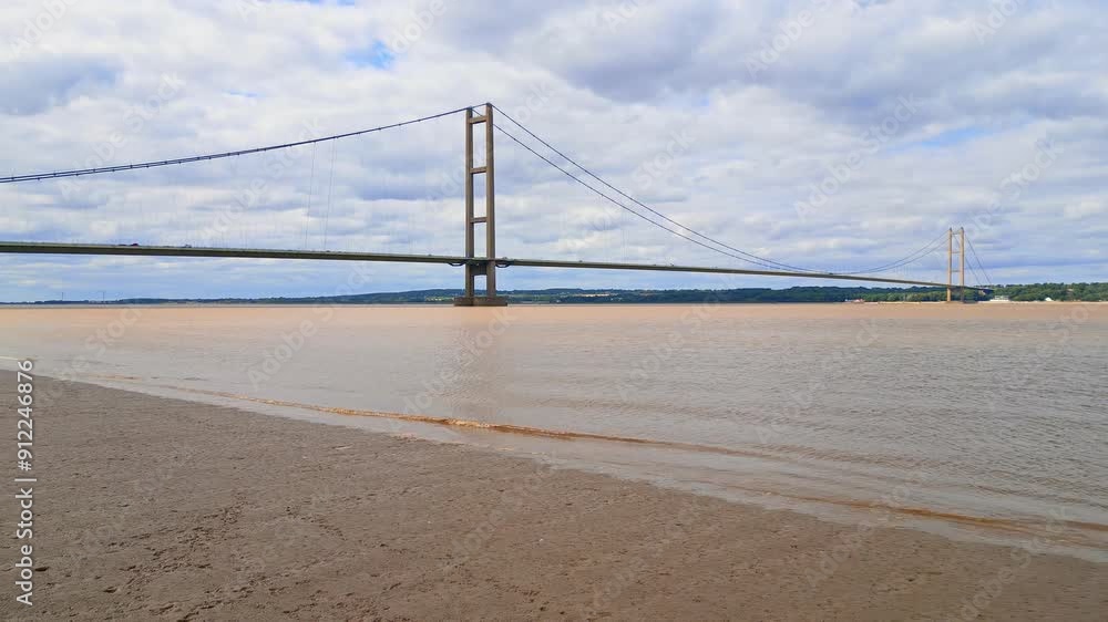 Aerial drone view of Humber Bridge, 12th largest suspension span, gracefully crossing River Humber, connecting Lincolnshire to Humberside with traffic. Aerial drone view of Humber Bridge, 12th largest suspension span, gracefully crossing River Humber, connecting Lincolnshire to Humberside with traffic.