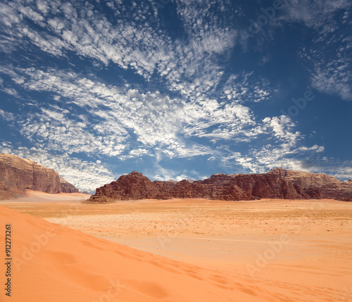 Wadi Rum Desert also known as The Valley of the Moon (against the sky with clouds)-- is a valley cut into the sandstone and granite rock in southern Jordan 60 km to the east of Aqaba