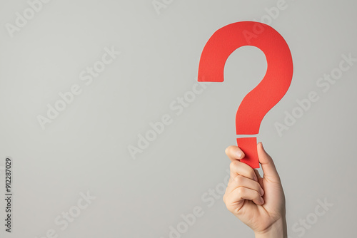 hand holding up a big red question mark made of paper isolated on clean smooth solid background photo