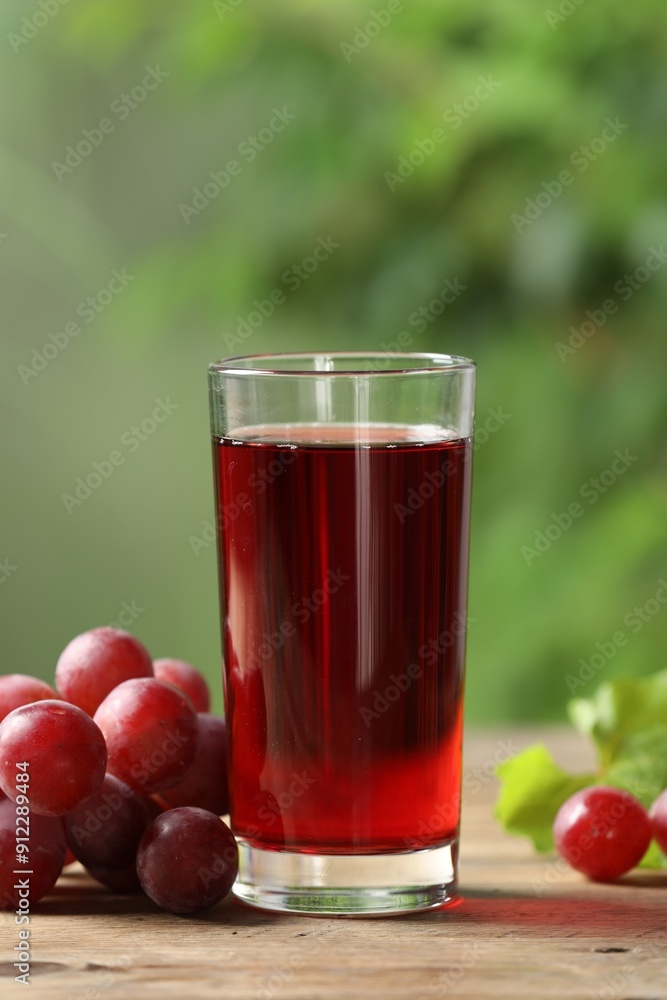 Tasty juice in glass and fresh grapes on wooden table Tasty juice in glass and fresh grapes on wooden table