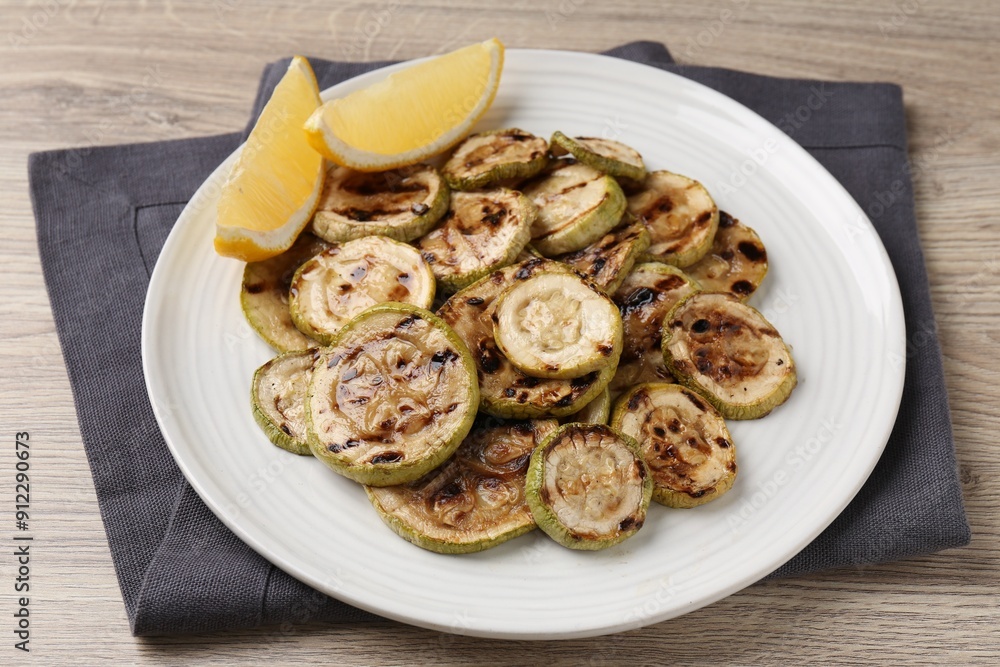 Tasty grilled courgette slices with lemon on wooden table Tasty grilled courgette slices with lemon on wooden table