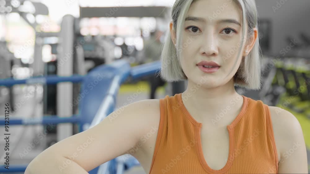 Happy young beautiful Asian woman in fitness outfit resting at the gym boxing ring during her work out break, smiling at camera Happy young beautiful Asian woman in fitness outfit resting at the gym boxing ring during her work out break, smiling at camera