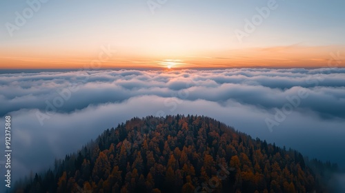 From a peak at sunset above the clouds a wonderful landscape stretches below bathed in a golden light effect as the last rays of the sun illuminate the autumn trees sunlight filter