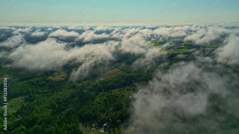 Clouds hover above lush green forests in a breathtaking aerial view Clouds hover above lush green forests in a breathtaking aerial view