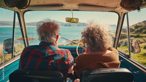 A senior couple traveling is taking a picture of the ocean from the back of a car
