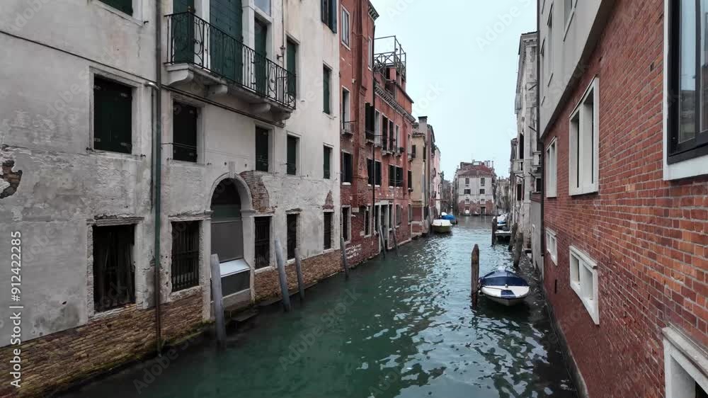 Perspective shot of the canal street of Venice, with moving water, boats alongside of walls of buildings Perspective shot of the canal street of Venice, with moving water, boats alongside of walls of buildings