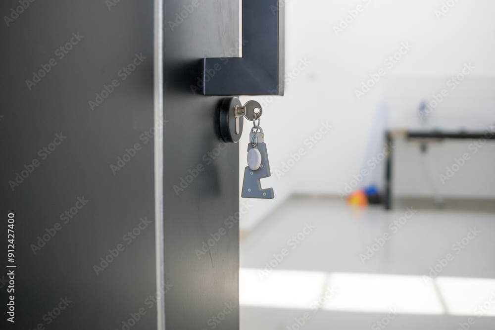 A house key with a key ring inserted at the door lock. Buy new home or concept A house key with a key ring inserted at the door lock. Buy new home or concept